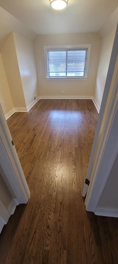 empty room with dark wood-style flooring, vaulted ceiling, and a wealth of natural light