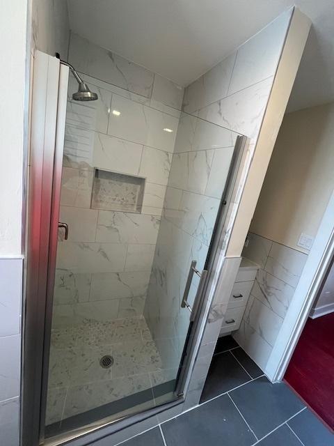 full bath with tile patterned floors, a stall shower, and tile walls