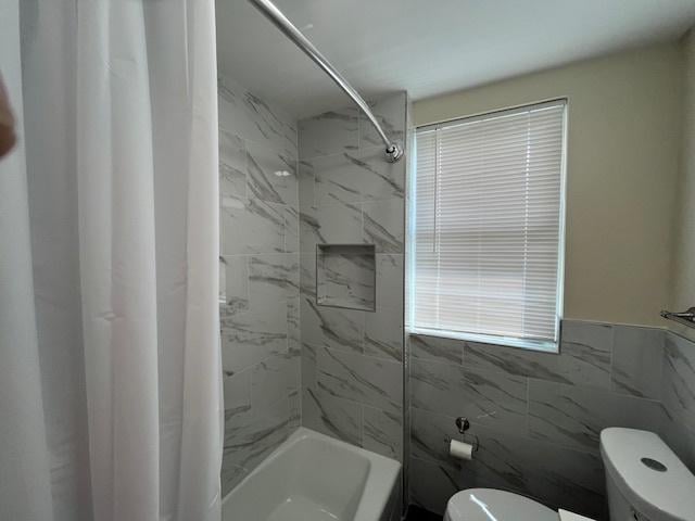 full bathroom with tile walls, shower / bath combo, and toilet