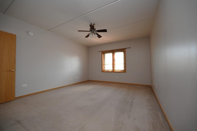 empty room featuring light colored carpet, a ceiling fan, baseboards, and a smoke detector