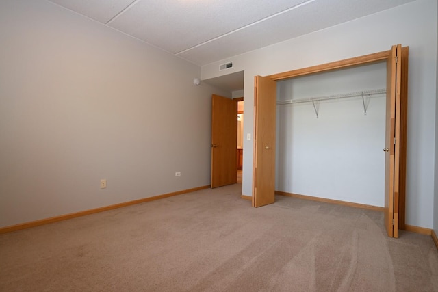 unfurnished bedroom featuring light carpet, baseboards, and a closet