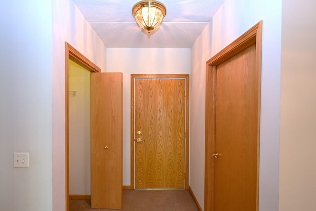 hallway with carpet flooring, a textured ceiling, and baseboards