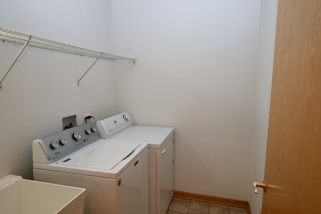 clothes washing area featuring independent washer and dryer, light tile patterned flooring, and baseboards