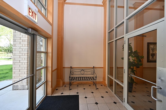 interior space with a high ceiling, light tile patterned floors, and baseboards