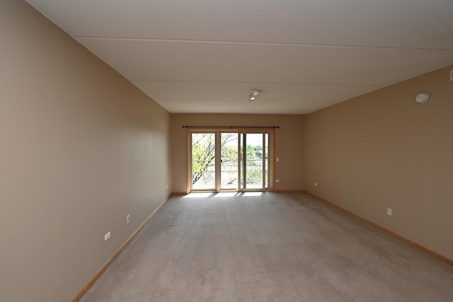 unfurnished room with light colored carpet, baseboards, and a smoke detector