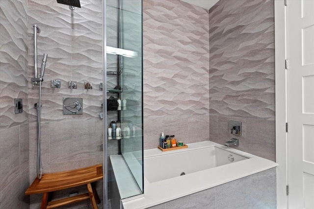 bathroom with a garden tub, tiled shower, and tile walls