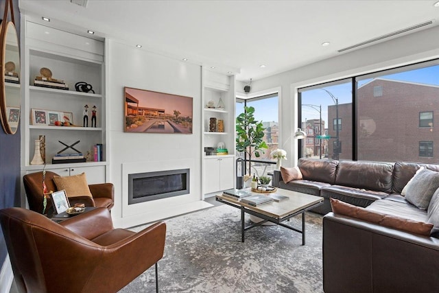 living area with a fireplace with flush hearth, built in shelves, and visible vents