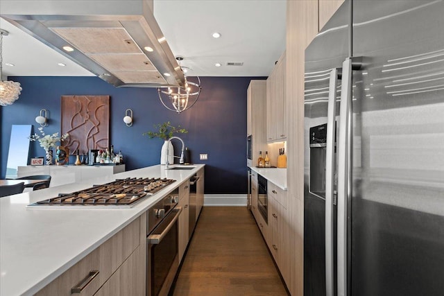 kitchen featuring dark wood-style flooring, stainless steel appliances, a sink, and light countertops