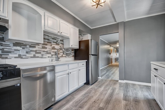 kitchen with white cabinetry, decorative backsplash, appliances with stainless steel finishes, light countertops, and light wood finished floors