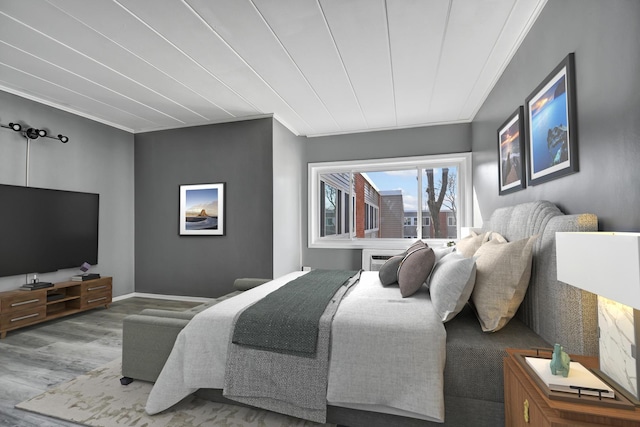 bedroom with ornamental molding and wood finished floors