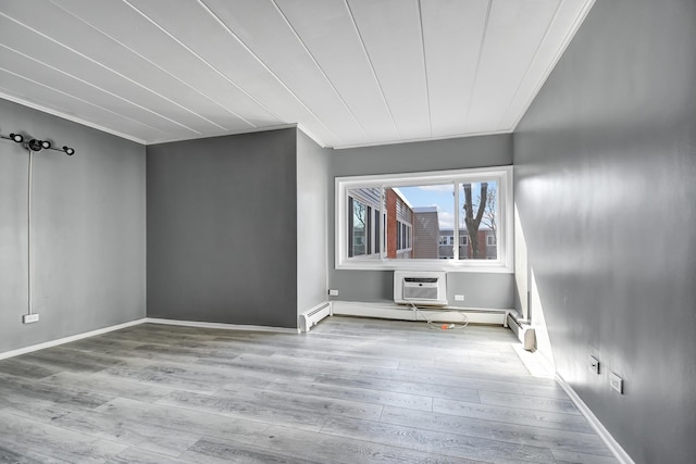 unfurnished room featuring baseboards, ornamental molding, wood finished floors, and an AC wall unit