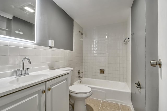 bathroom with shower / bathtub combination, toilet, tile walls, vanity, and tile patterned flooring