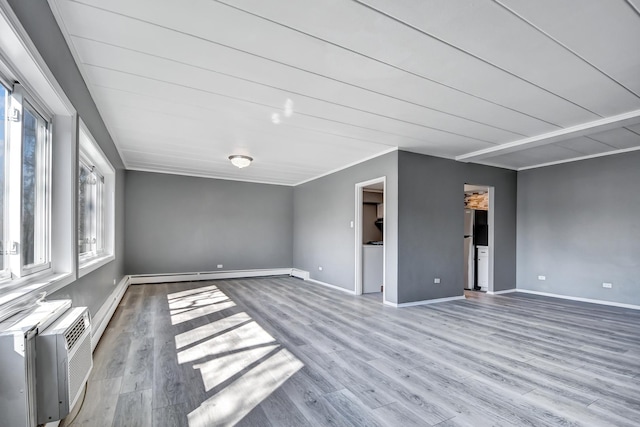 unfurnished living room with baseboards, wood finished floors, a wall unit AC, and a baseboard radiator