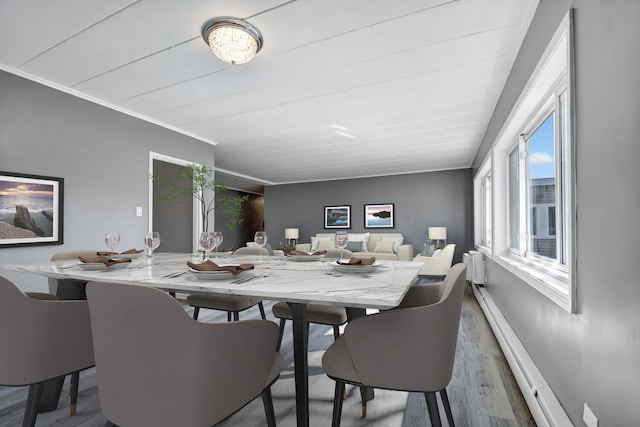 dining room with a wealth of natural light, wood finished floors, ornamental molding, and baseboard heating