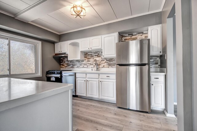kitchen with appliances with stainless steel finishes, light countertops, white cabinets, backsplash, and crown molding