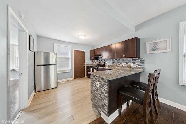 509 W 81st St, Chicago, IL 60620 - kitchen featuring stainless steel appliances, a kitchen bar, dark brown cabinetry, decorative backsplash, and a peninsula