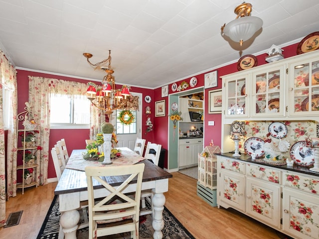 17237 Greenbay Ave, Lansing, IL 60438 - dining space with visible vents, crown molding, a chandelier, and light wood-style floors