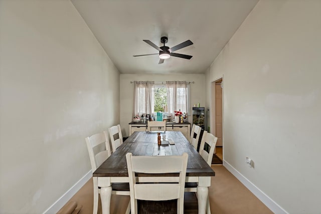 dining room featuring baseboards, light carpet, and a ceiling fan