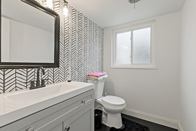 bathroom with toilet, backsplash, vanity, and baseboards