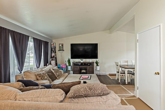 living area featuring lofted ceiling with beams, a fireplace, and baseboards