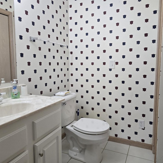 half bath with tile patterned flooring, wallpapered walls, toilet, vanity, and baseboards