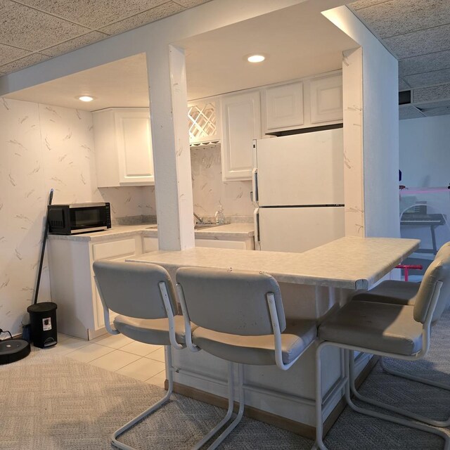 kitchen with white cabinets, freestanding refrigerator, and light countertops