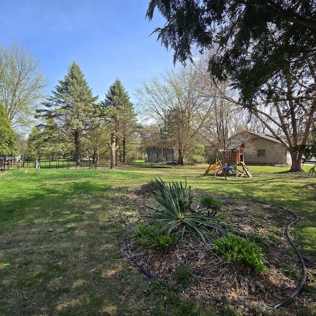 view of yard with a trampoline, a playground, and fence