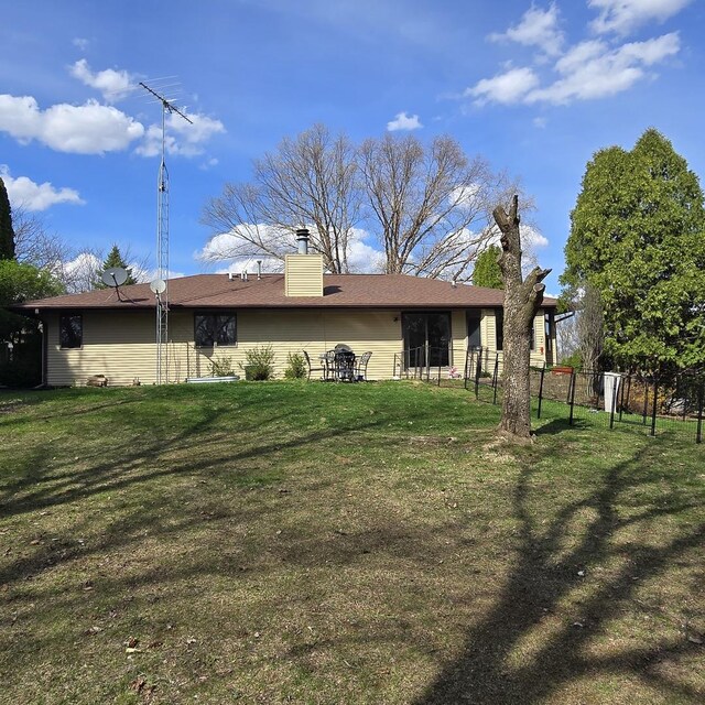back of house with a lawn, fence, and a chimney