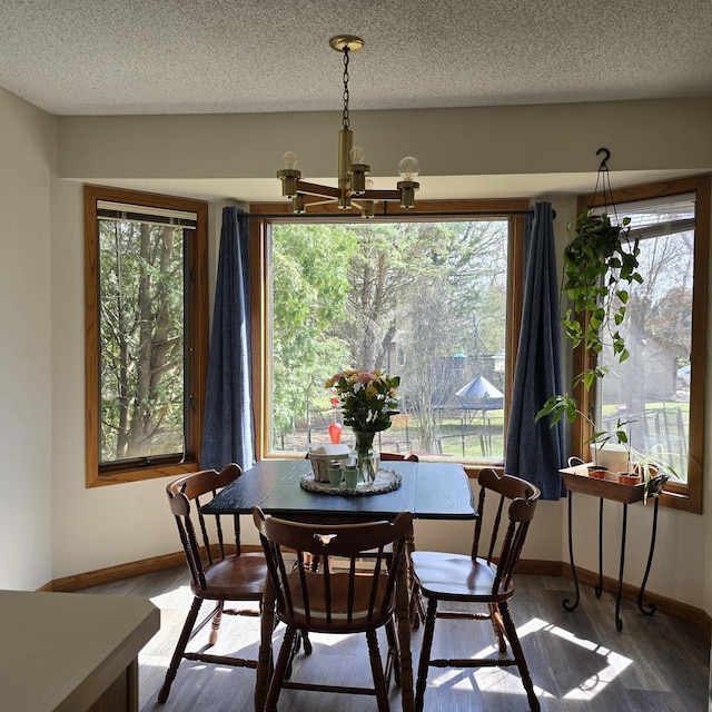 dining area with an inviting chandelier, a textured ceiling, wood finished floors, and baseboards