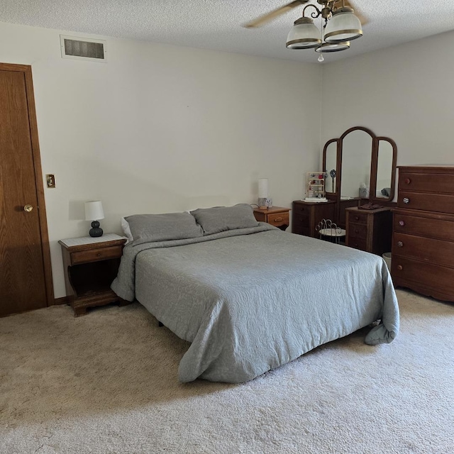 carpeted bedroom with visible vents, ceiling fan with notable chandelier, and a textured ceiling