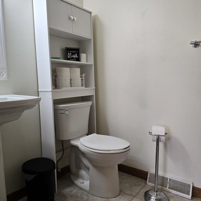 half bath with toilet, tile patterned flooring, visible vents, and baseboards
