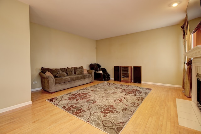 living room featuring wood finished floors, a tiled fireplace, and baseboards