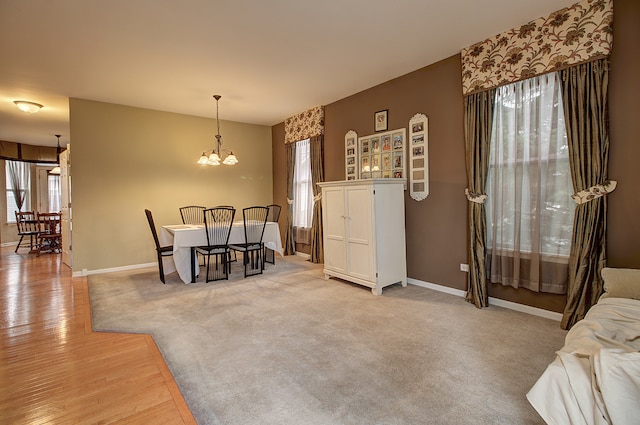 dining area with baseboards, light wood-type flooring, and a notable chandelier