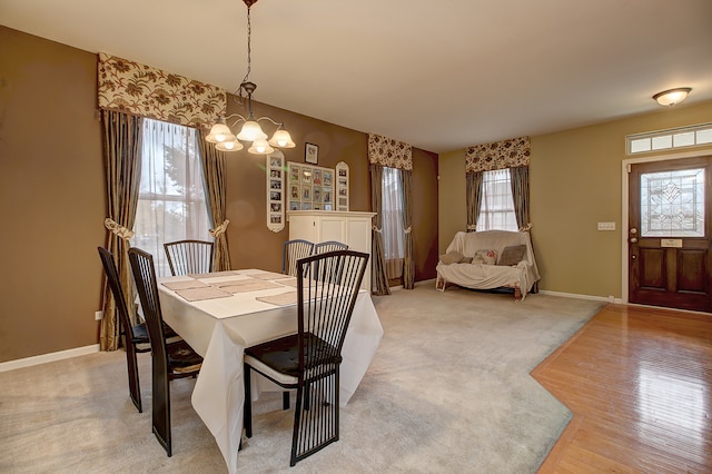 dining area with baseboards, an inviting chandelier, and light wood finished floors