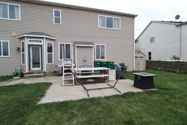 rear view of property featuring a patio, an outdoor structure, a shed, a lawn, and fence