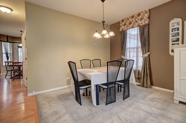 dining room with light wood-type flooring, a notable chandelier, and baseboards
