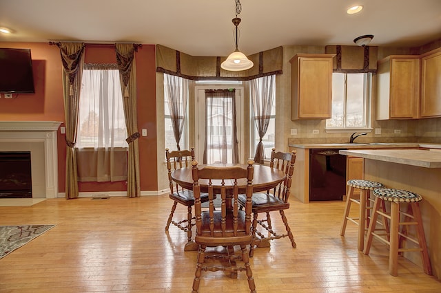 dining area featuring a fireplace with flush hearth, light wood-type flooring, and recessed lighting