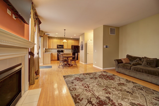 living area featuring light wood finished floors, recessed lighting, visible vents, and baseboards