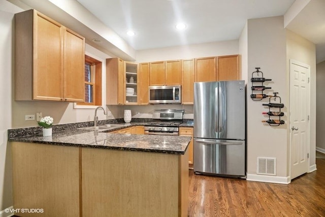 kitchen with visible vents, appliances with stainless steel finishes, a sink, dark stone countertops, and a peninsula