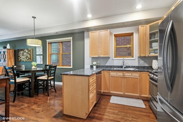 kitchen featuring light brown cabinetry, stainless steel appliances, a sink, and a peninsula