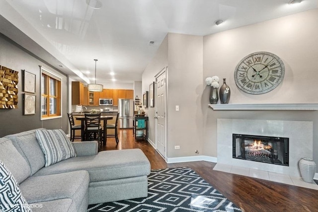 living room featuring baseboards, dark wood-style flooring, and a tile fireplace