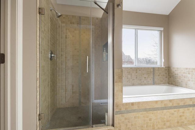 bathroom featuring a stall shower and a bath
