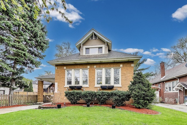 view of front of home featuring brick siding, fence, a shingled roof, and a front yard
