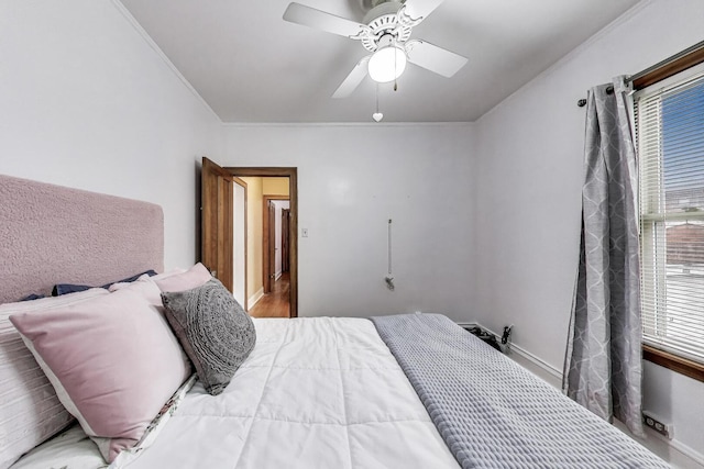 bedroom featuring crown molding, a ceiling fan, baseboards, and wood finished floors