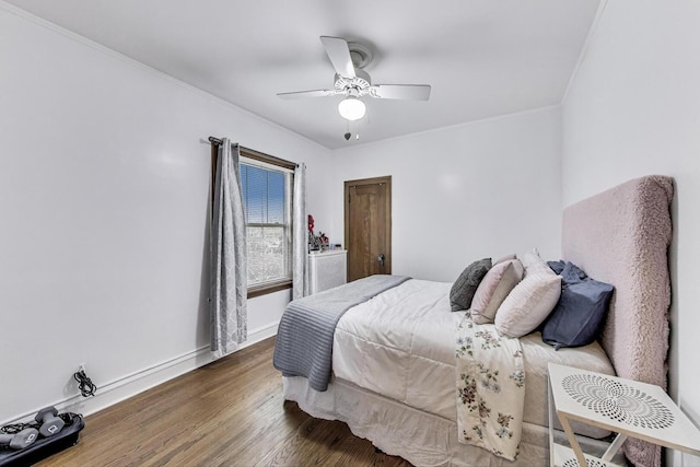 bedroom featuring crown molding, a ceiling fan, baseboards, and wood finished floors