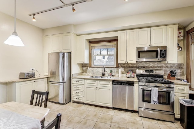 kitchen featuring a sink, decorative backsplash, appliances with stainless steel finishes, and rail lighting