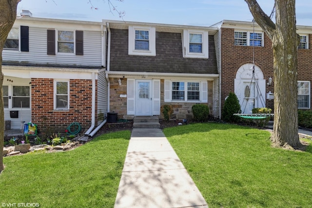 multi unit property with brick siding, a shingled roof, a front lawn, and stone siding