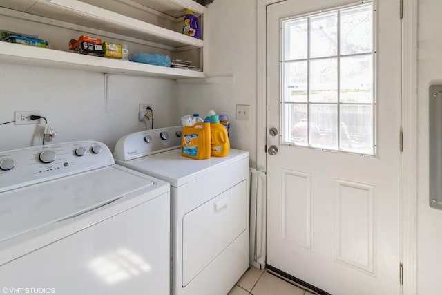 clothes washing area featuring light tile patterned floors, washing machine and clothes dryer, and laundry area