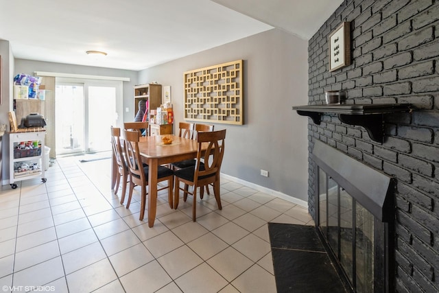 dining space with a fireplace, light tile patterned floors, and baseboards