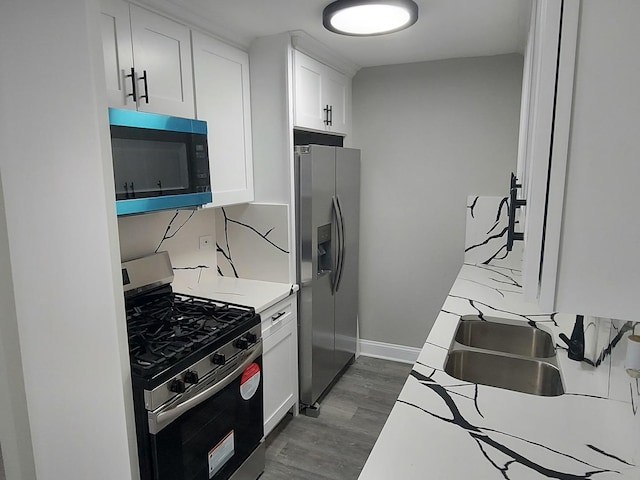 kitchen featuring white cabinetry, a sink, appliances with stainless steel finishes, dark wood-style floors, and baseboards